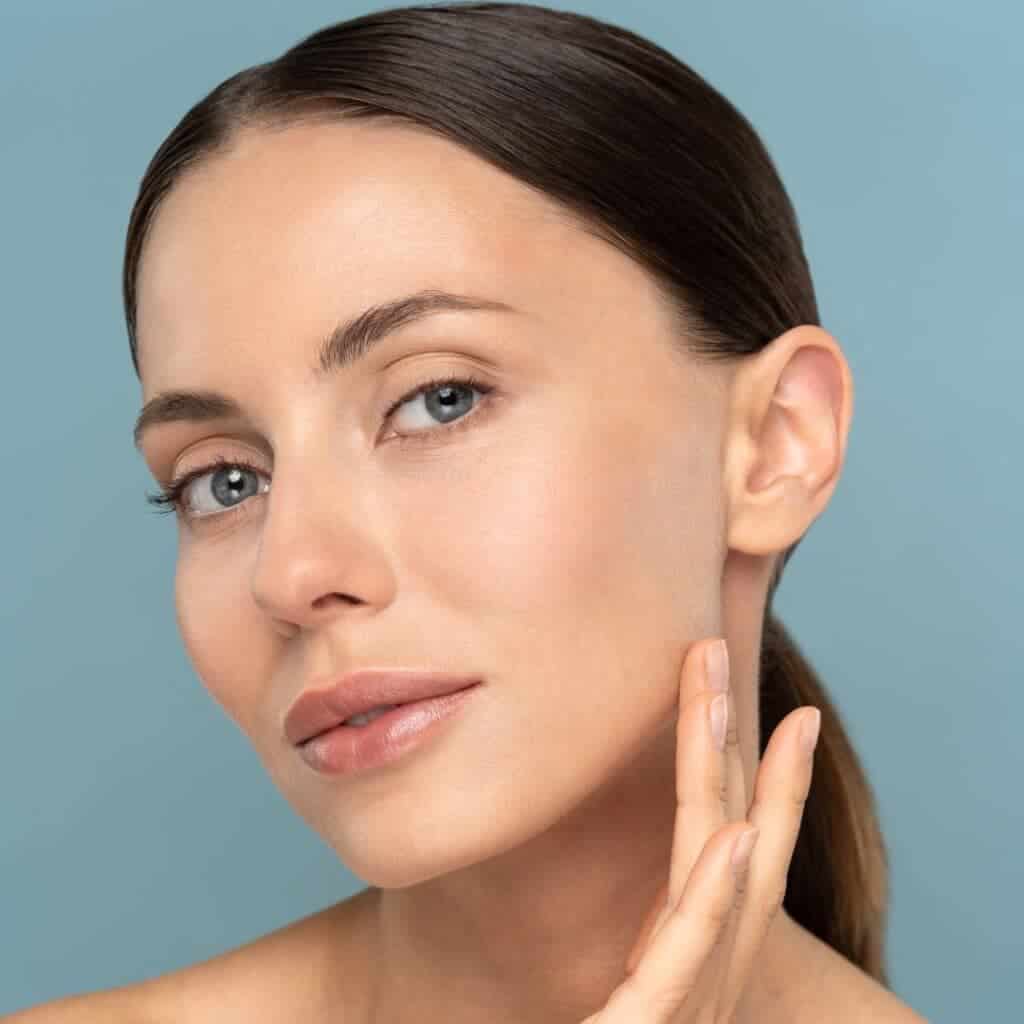 Donna con pelle luminosa e naturale, toccando il viso.